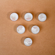 Six gemstone tealight candles with white wax on a brown surface, crystal decor